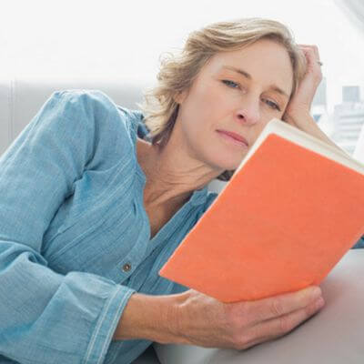middle-aged woman on her couch reading 