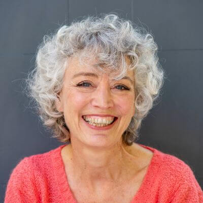 close up portrait of happy older woman smiling against a gray wall