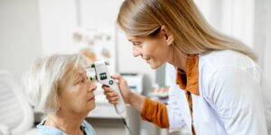 younger female ophthalmologist checks an older female patient’s vision