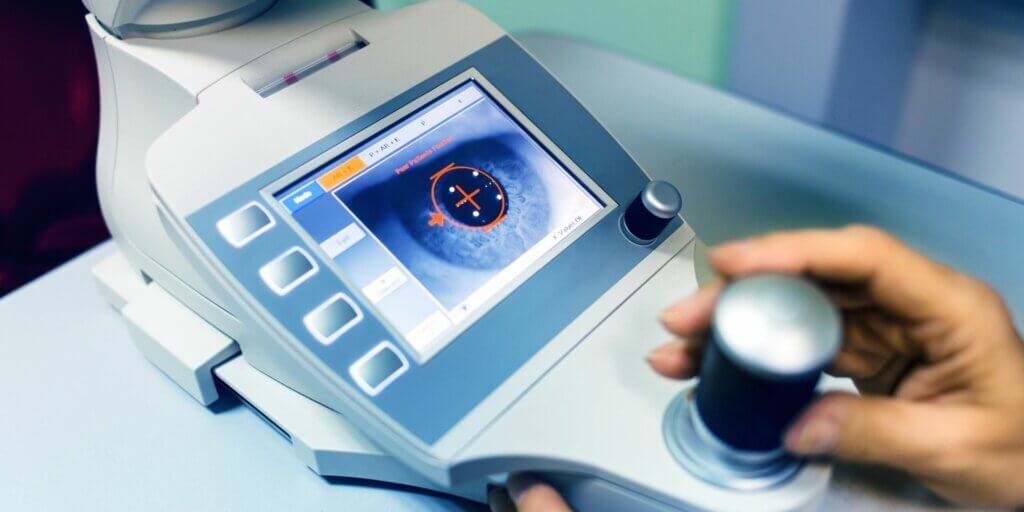 doctor using a machine to examine a patient's eye for corneal ulcer causes